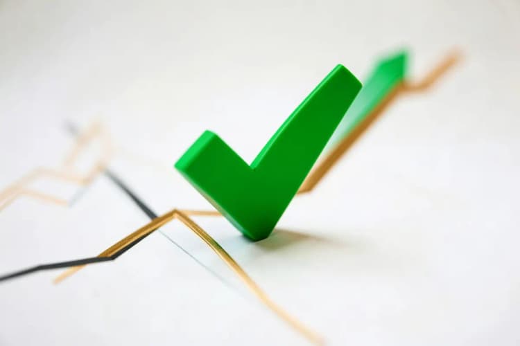 Sinal de 'check' verde sobreposto a um gráfico de desempenho positivo, indicando aprovação e bons resultados.