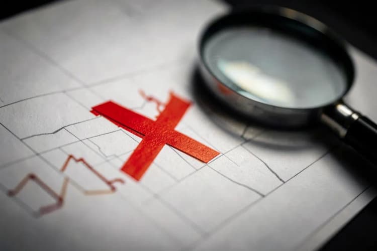 Sinal de 'X' vermelho sobreposto a um gráfico de desempenho em queda, com uma lupa ao lado, indicando a necessidade de ação corretiva.
