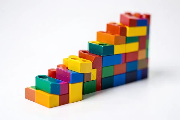 Uma pilha de blocos de construção coloridos formando uma escada ascendente, simbolizando crescimento e organização.