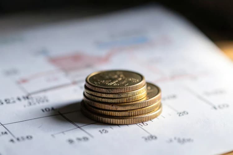 Moedas de dinheiro empilhadas em frente a um gráfico de crescimento.