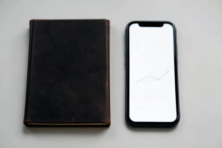 Um notebook fechado ao lado de um celular exibindo um gráfico simples.