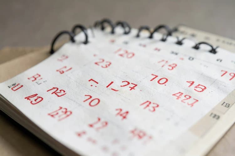 Um calendário com dias marcados em vermelho, simbolizando a passagem do tempo e a inatividade.