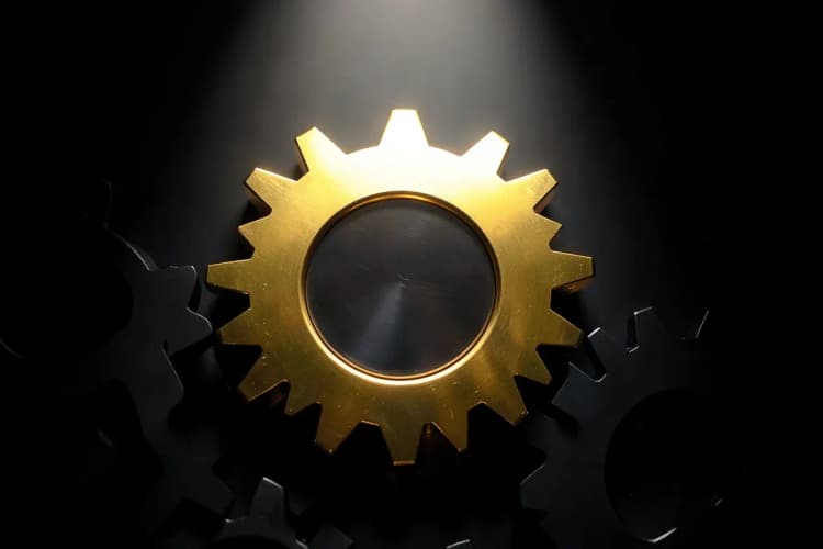 Uma engrenagem de metal dourado encaixando perfeitamente em um conjunto de outras engrenagens menores, simbolizando colaboração e funcionamento.